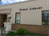 Public Library building with white book drop, bike rack at front entrance